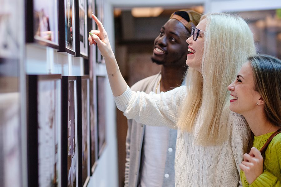 Art Gallery Insurance - Three Young Students Looking at a Picture on the Wall in an Art Photo Gallery