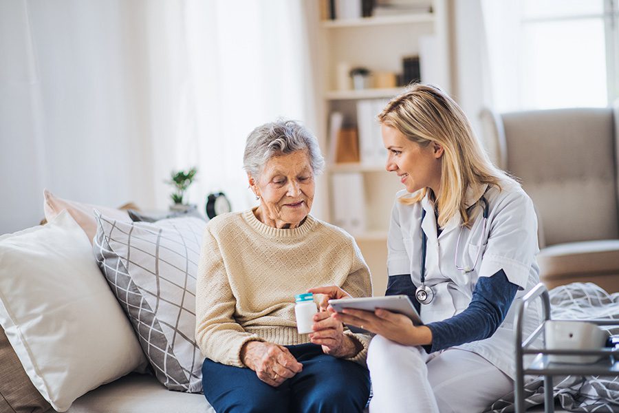 Home Health Care Business Insurance - A Health Professional Visiting a Patient at Home Explains How to Take Pills to a Senior Woman