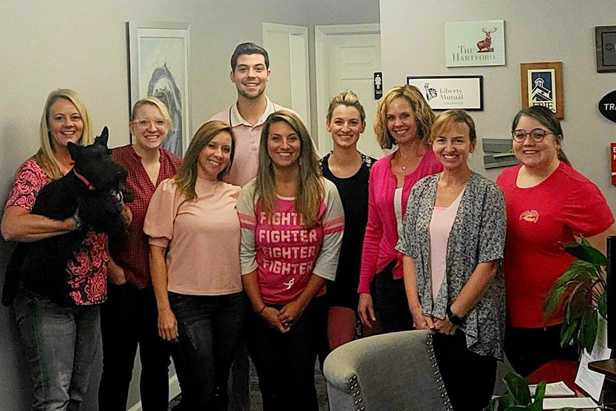 Community Involvement - Summit Insurance Group Inc Team Standing Together in the Office With a Dog